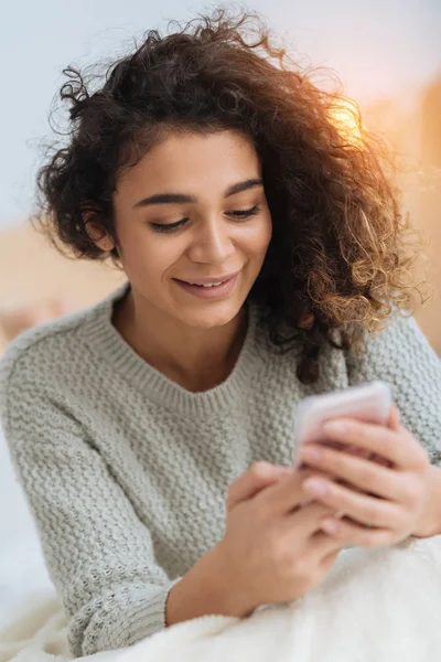 Chica alegre leyendo mensaje y sonriendo en casa — Foto de Stock