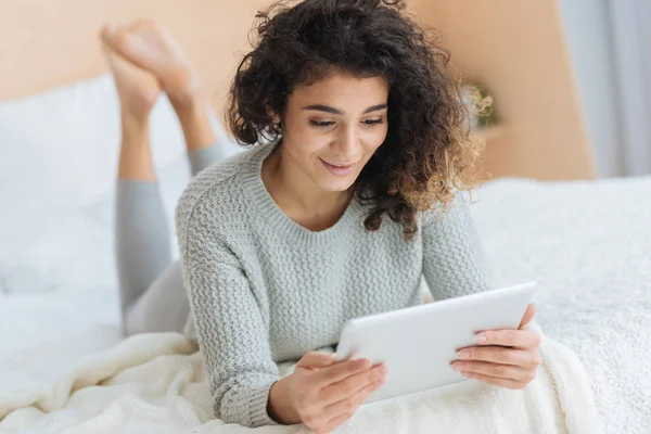 Очаровательная девушка смотрит на планшетный компьютер и улыбается — стоковое фото