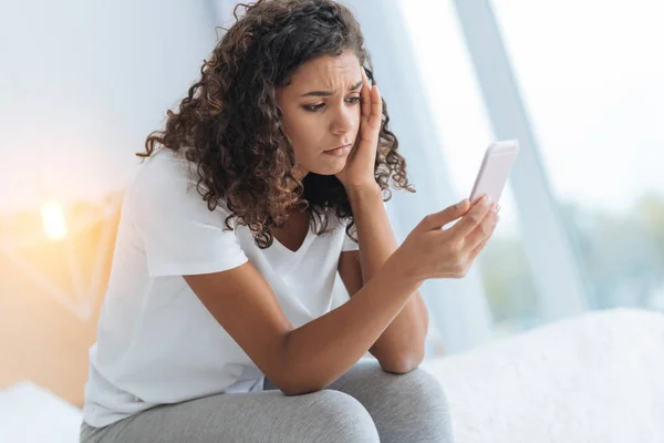 Menina triste não pode acreditar em seus olhos enquanto olha para o smartphone — Fotografia de Stock