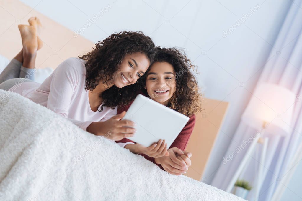 Smiling curly haired siblings using touchpad together
