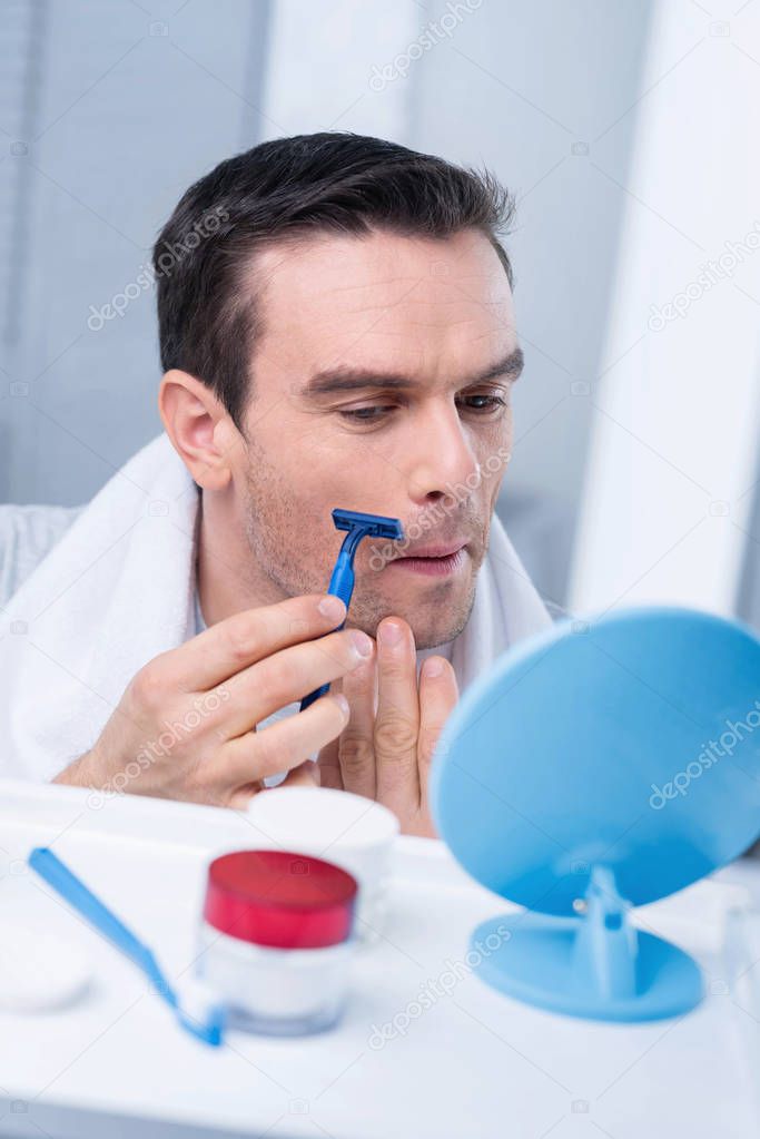 Focused attractive man getting rid of bristles
