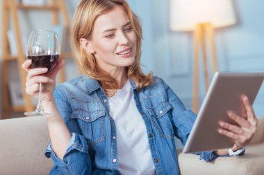 Düşünceli kadın modern bir tablet tutarken şarap içme