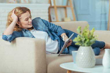 Bir tablet üzerine bir kitap okuma ve gülümseyen pozitif rahatlatıcı kadın