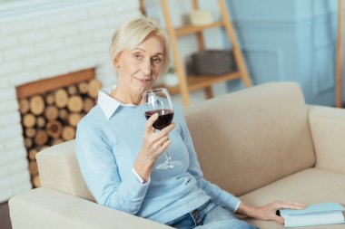 Evde oturan ve kırmızı şarap içme sakin neşeli emekli