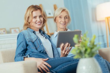 Kanepede oturan ve modern bir tablet holding neşeli kadın