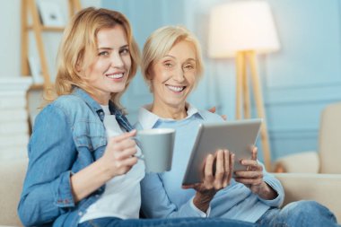 Bir fincan bir tablet ile oturup onu Büyükanne süre tutan gülümseyen kadın