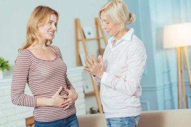 Hamile kadına bakarak ve gülümseyen mutlu kadın kıdemli