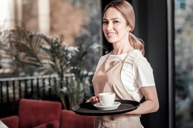 Ayakta ve bir fincan kahve ile bir tepsi tutarak güzel garson