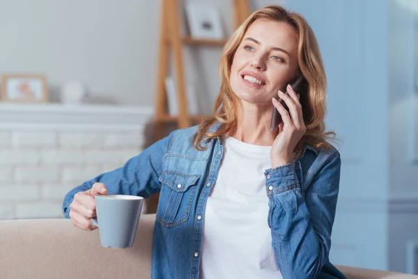 Glad ung kvinna som pratar i telefonen när man dricker te — Stockfoto