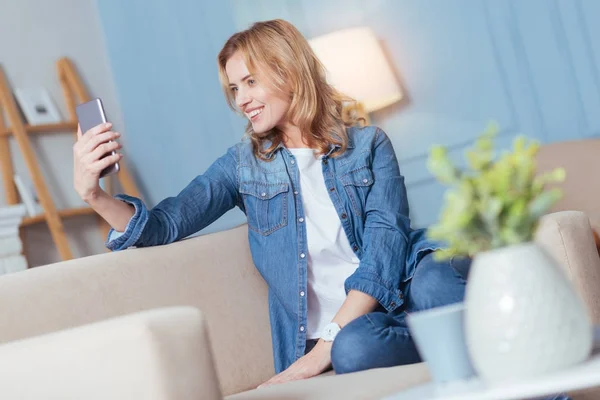 Feliz sorrindo mulher sentada e tirando uma foto de si mesma — Fotografia de Stock