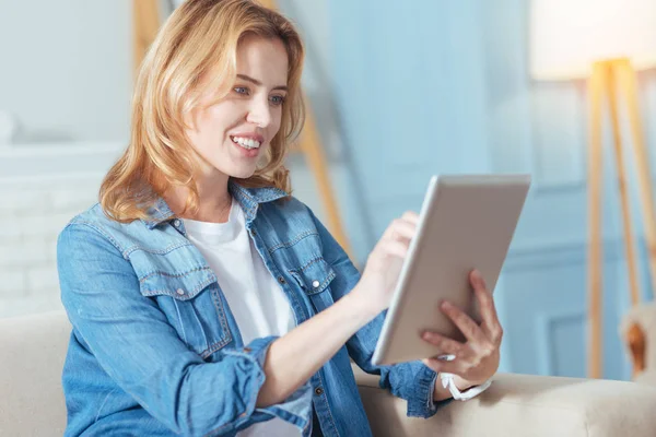 Mujer joven linda mirando atento mientras se utiliza la tableta — Foto de Stock