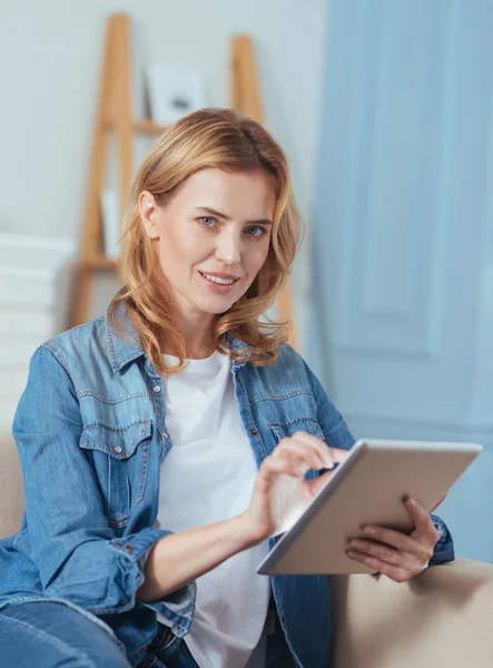 Mujer bastante agradable usando su dispositivo moderno y sonriendo —  Fotos de Stock