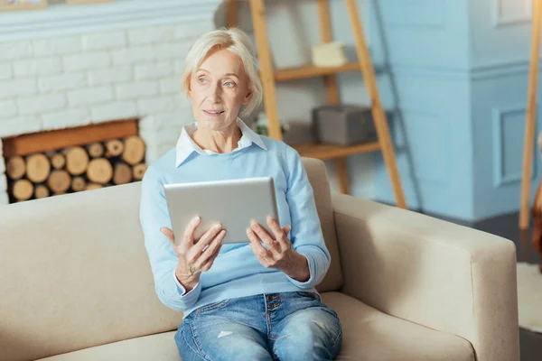 Inteligente pensionista tranquilo sentado con un gadget moderno y pensando — Foto de Stock