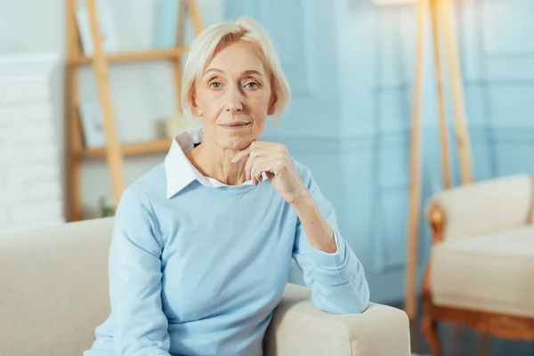 Niedliche alte Frau sitzt auf einem Sofa und wartet auf ihre Verwandten — Stockfoto