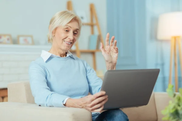 Розумна старша жінка посміхається під час відеодзвінка з онуками — стокове фото
