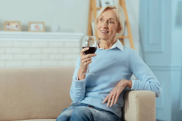 Мирная пожилая женщина пьет вино и смотрит вдаль — стоковое фото