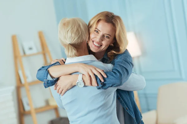 Warm hugs of a cheerful young woman and her granny — Stock Photo, Image