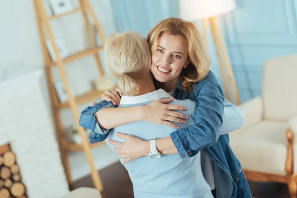 Gelukkig jonge vrouw die haar vriendelijk senior relatieve knuffelen — Stockfoto