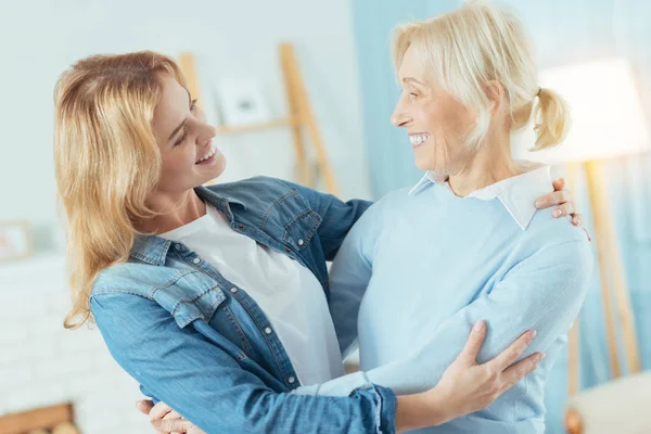Позитивные женщины двух поколений смотрят друг на друга и улыбаются — стоковое фото