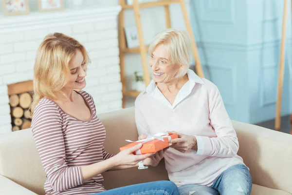 Vriendelijke attente oma geven een mooie aanwezig is om haar kleinkind — Stockfoto