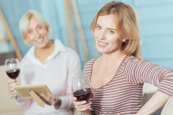Cheerful relatives sitting on a sofa and drinking red wine together — Stock Photo, Image