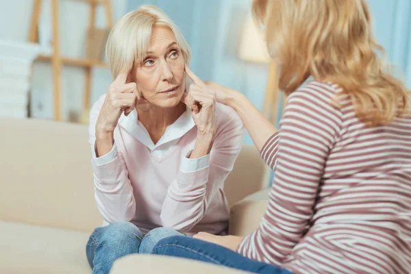 Bir baş ağrısı yaparken endişe arayan ciddi üst düzey kadın