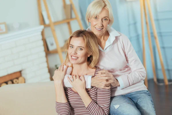 Cheerful senior woman hugging her relative while being at home — Stock Photo, Image