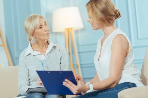 Cheerful smart financial advisor smiling while helping an aged woman — Stock Photo, Image