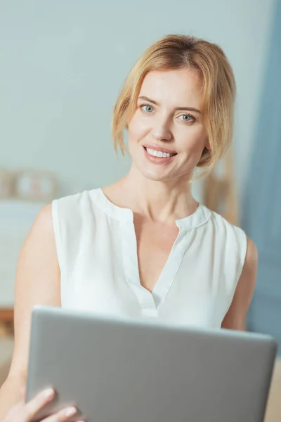 Frumoasă femeie veselă în picioare și ținând un laptop convenabil — Fotografie, imagine de stoc