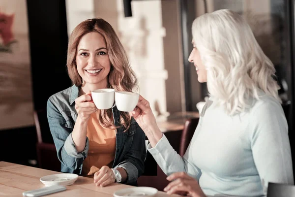 Mujer joven sonriente sentada con su abuela mayor — Foto de Stock