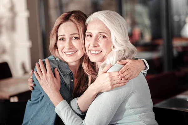 Ganska ung kvinna kramar hennes vänliga leende mormor — Stockfoto