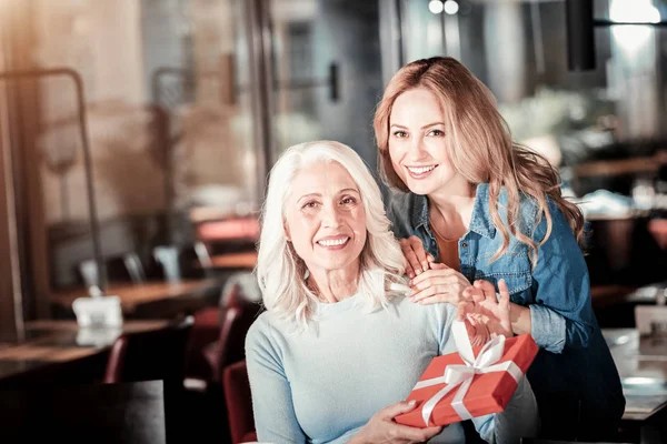 Wanita senior yang bahagia menunjukkan hadiah yang indah dan tersenyum — Stok Foto
