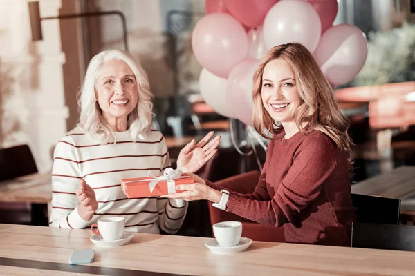 Upphetsad ung kvinna hälsning hennes senior mormor på hennes födelsedag — Stockfoto