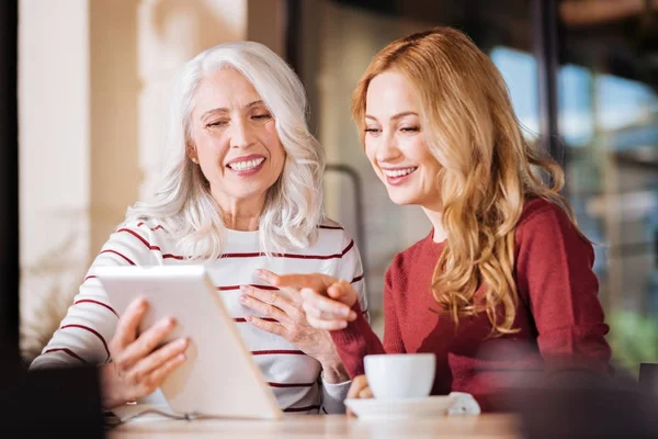 Позитивні дружні жінки сміються, дивлячись на екран планшета — стокове фото