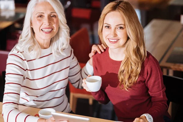Vidám idős nő mosolyogva, miközben ül egy kávézóban, unokája — Stock Fotó