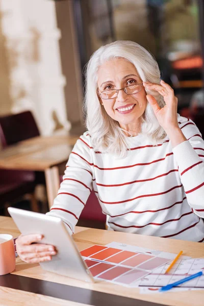 Positiv optimistisk senior kvinna sitter med en modern gadget — Stockfoto