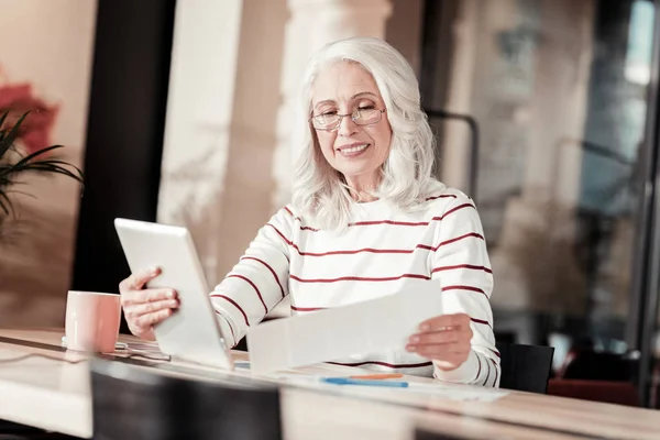 Positiv senior kvinna som arbetar sittande med hennes gadget — Stockfoto