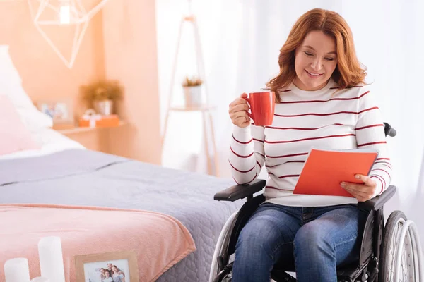 Alerta sonriente mujer discapacitada sosteniendo una taza y un cuaderno — Foto de Stock