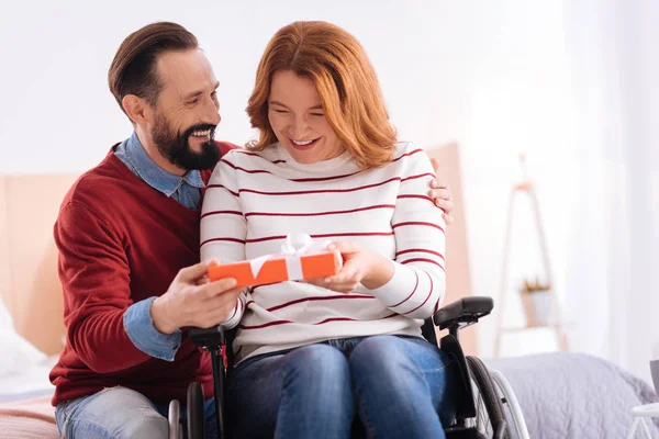 Glimlachende man een geschenk te geven aan een gelukkige gehandicapte vrouw — Stockfoto