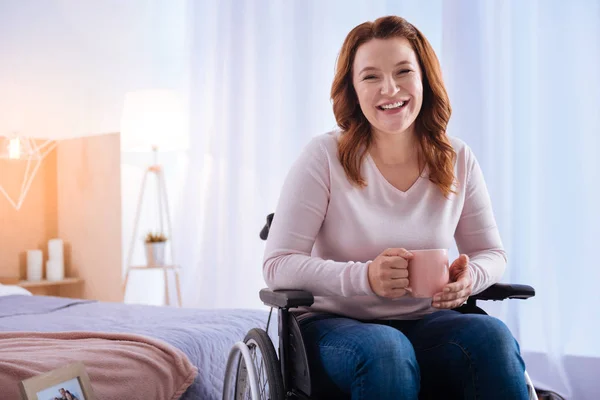 Смеющаяся, ликующая женщина-инвалид держит чашку — стоковое фото