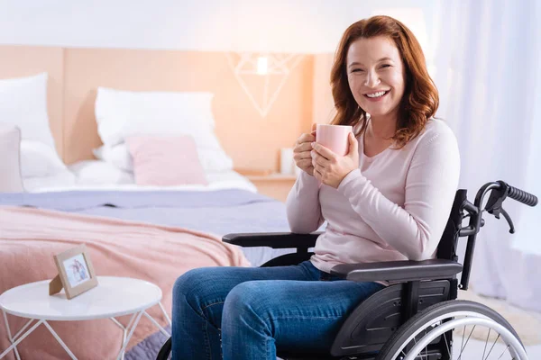 Смеющаяся женщина-инвалид пьет чай — стоковое фото