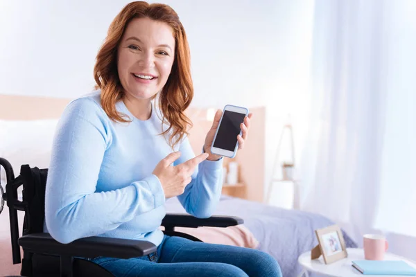 Mujer discapacitada sonriendo y señalando su teléfono — Foto de Stock