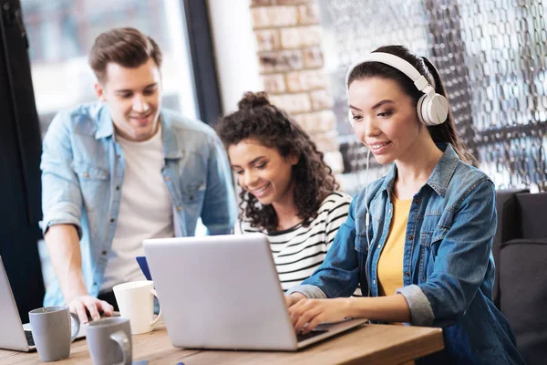 Chica sonriente con auriculares y trabajando en el portátil — Foto de Stock