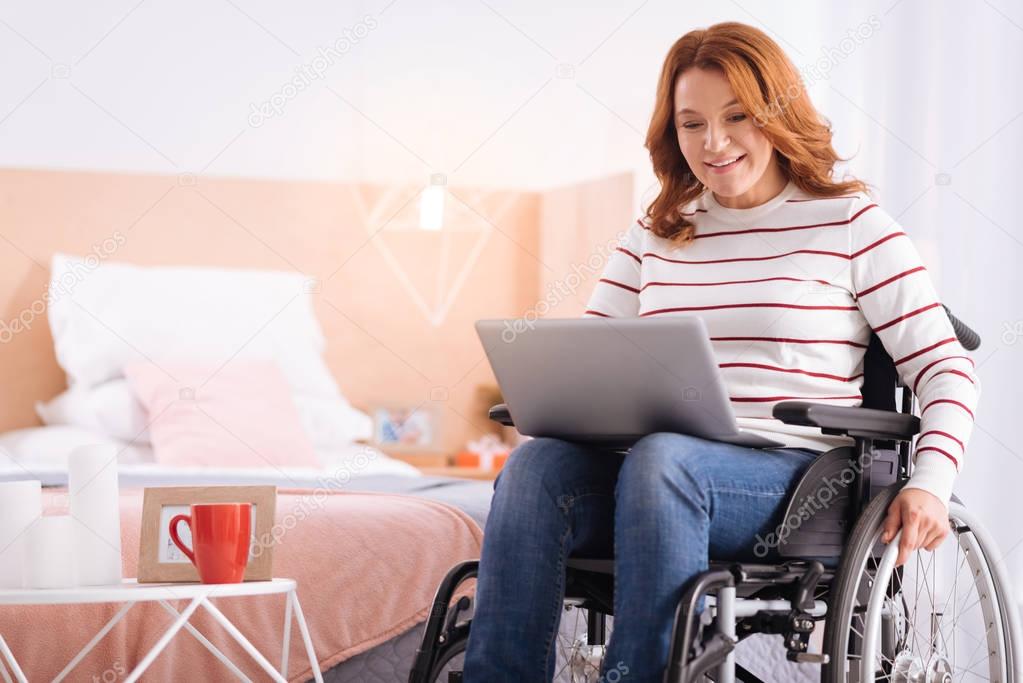 Smiling incapacitated woman working on her laptop