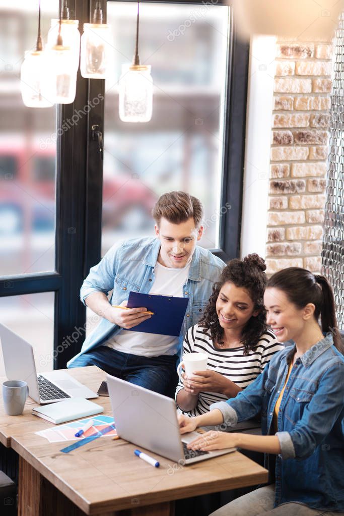 Overjoyed man and two girls sitting at the table working