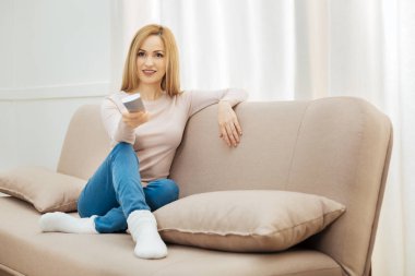 Uzaktan kumanda ile kanepede oturan mutlu kadın