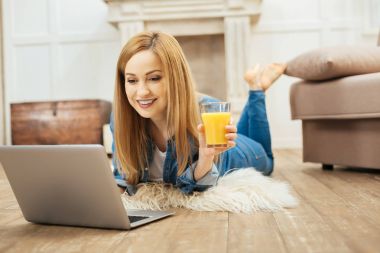 Çalışma ve bir bardak meyve suyu tutan neşeli kadın