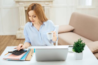 Bir fincan çay çalışırken tutan gülümseyen kadın