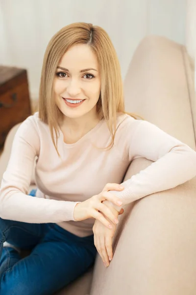 Schöne blonde dunkeläugige Frau sitzt auf dem Sofa — Stockfoto