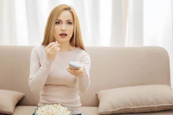 Mulher surpresa comendo pipocas enquanto assiste TV — Fotografia de Stock